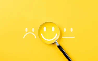 Symbolbild UX-Design - Smiley unter Lupe für zufriedene User